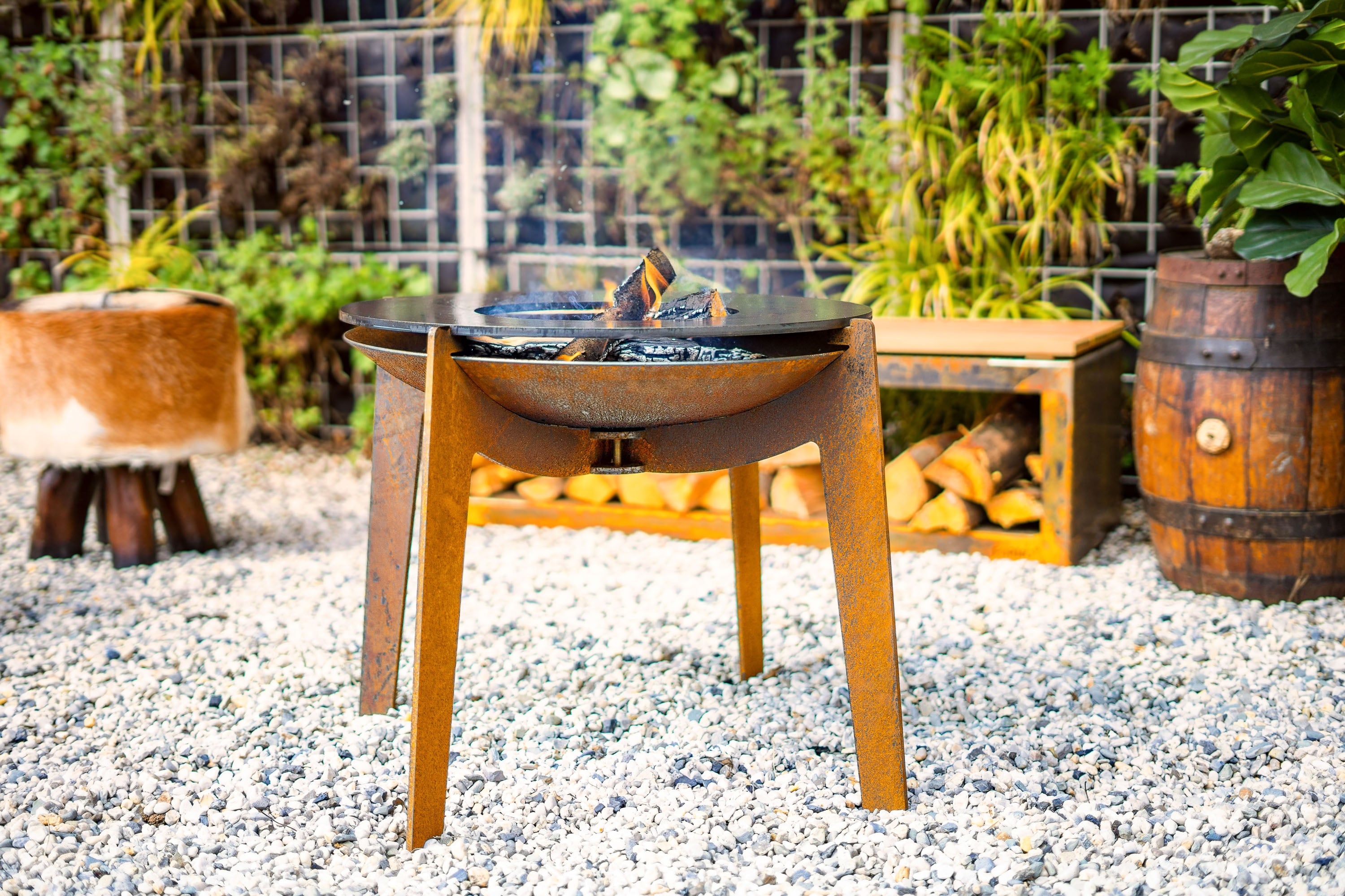 Wooden fire pit table with flames in a garden setting