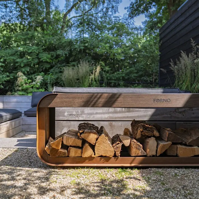 Wooden & corten firewood holder with stacked logs in a garden setting, featuring the brand 'Forno'.