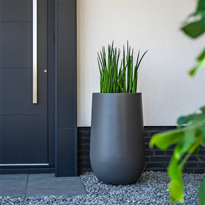 tall dark grey rounded planter situated outside front door planted with greenery