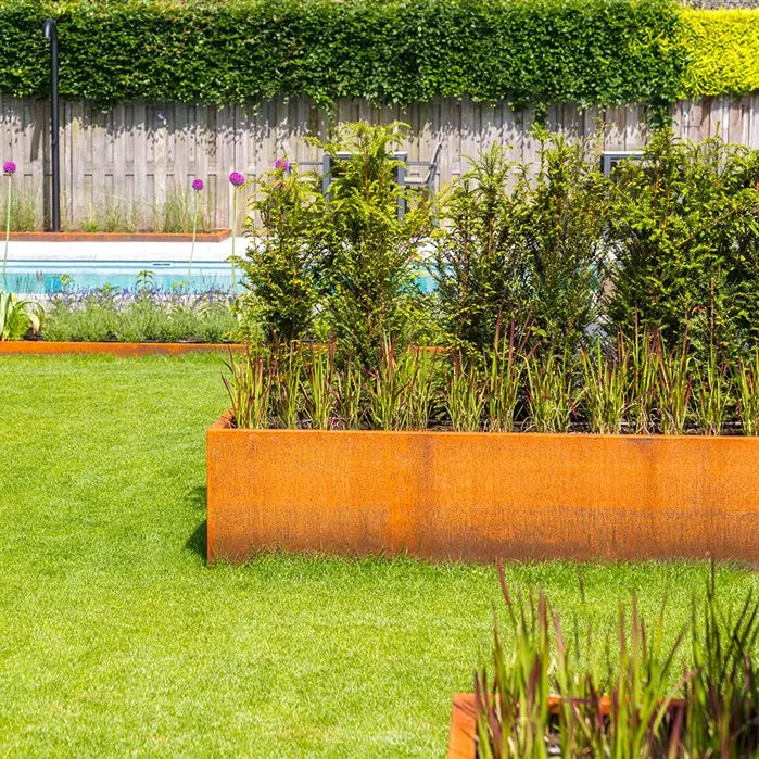 corten steel L shape garden planter on law planted with shrubs