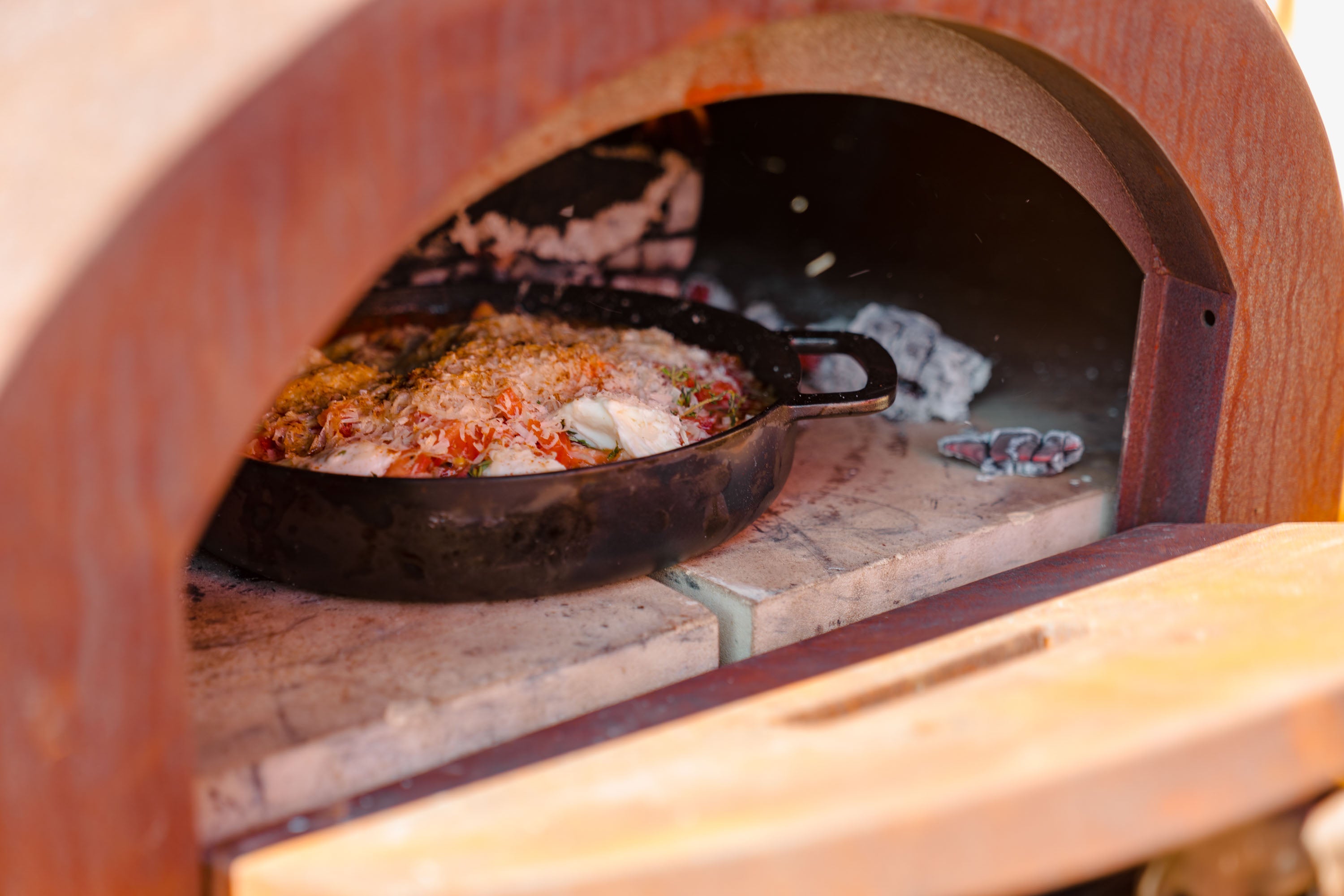 Wood-fired oven with a pizza inside, showing the cooking process.