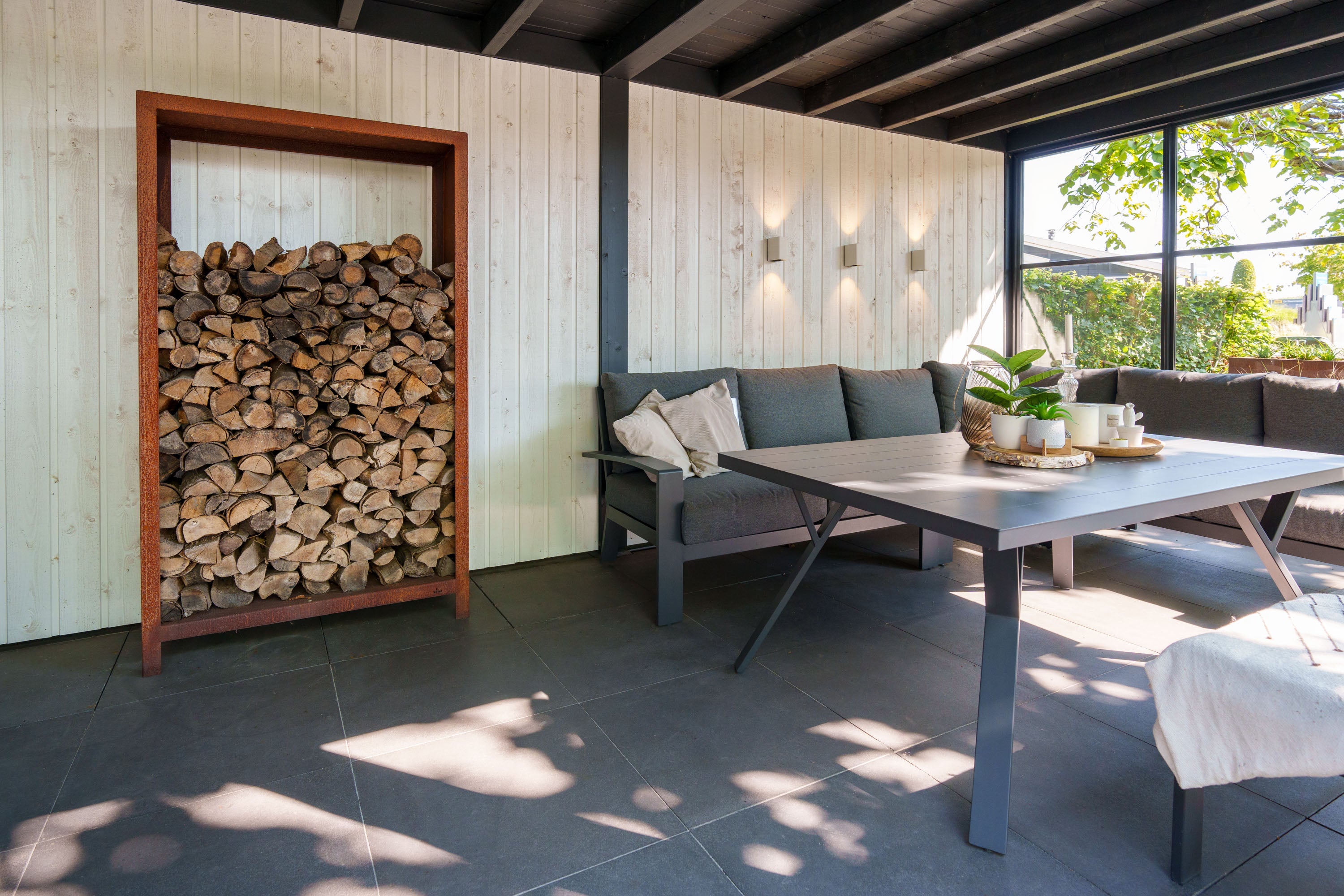 Outdoor patio area with firewood storage, table, and seating