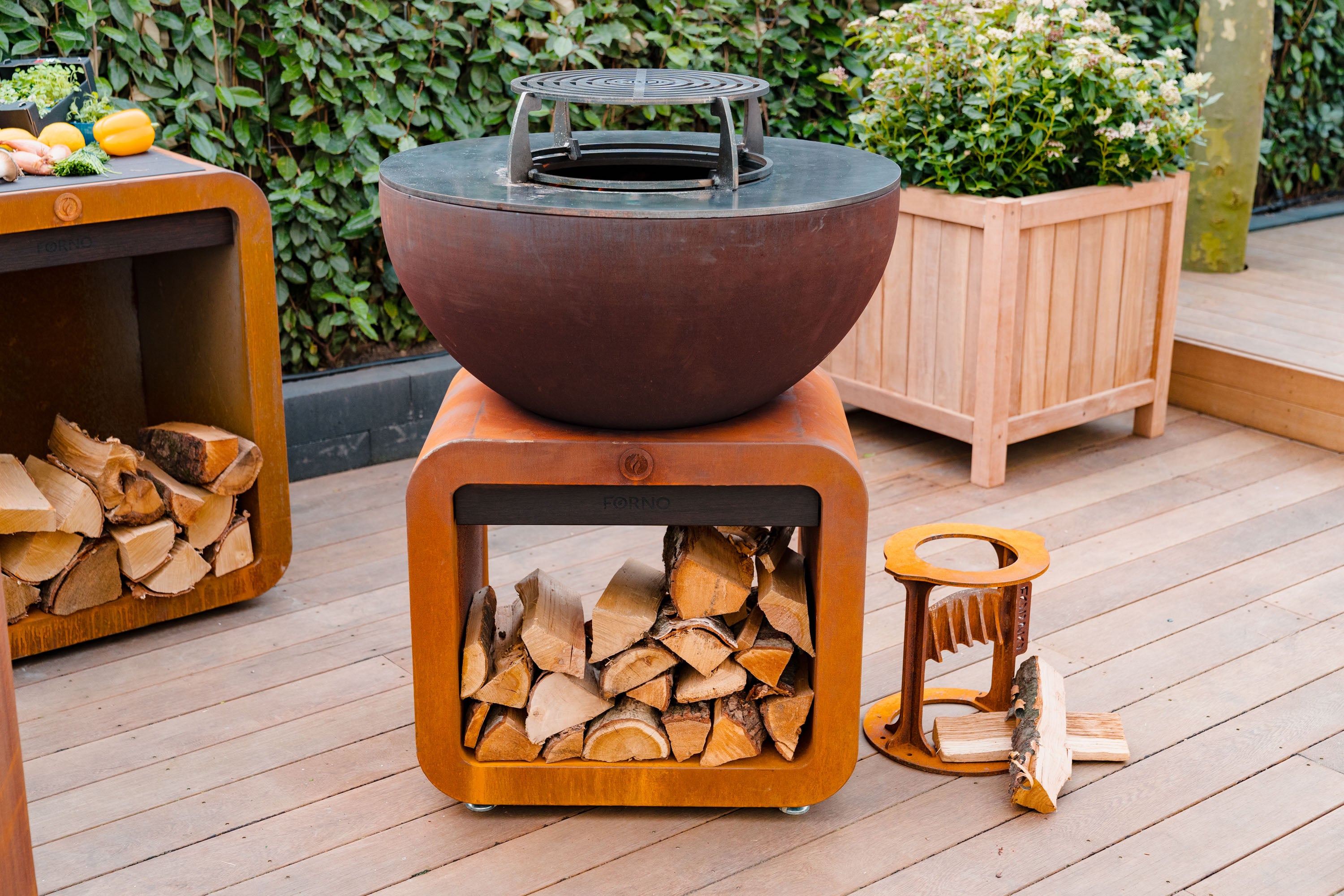 round corten bbq and grill on wood store with wood splitter next to it