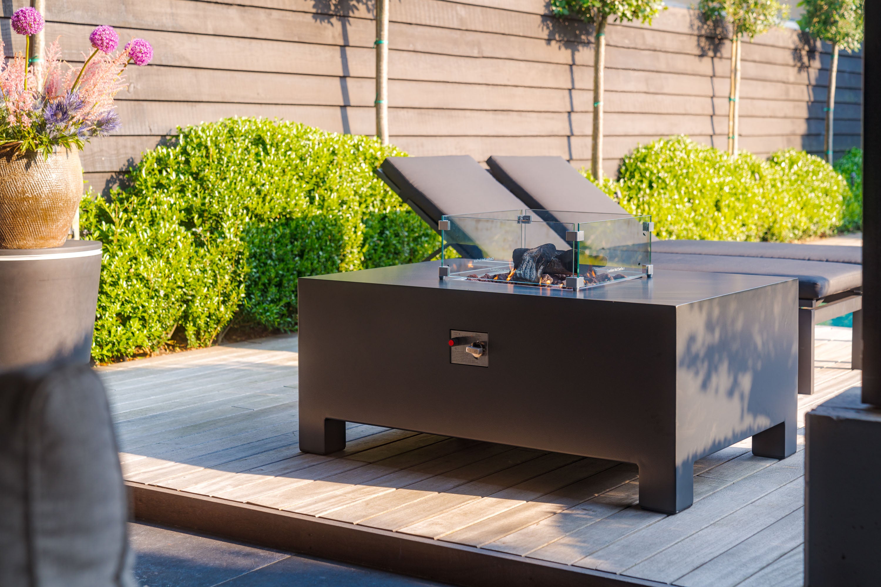 black lit gas fire table on decking next to sun loungers