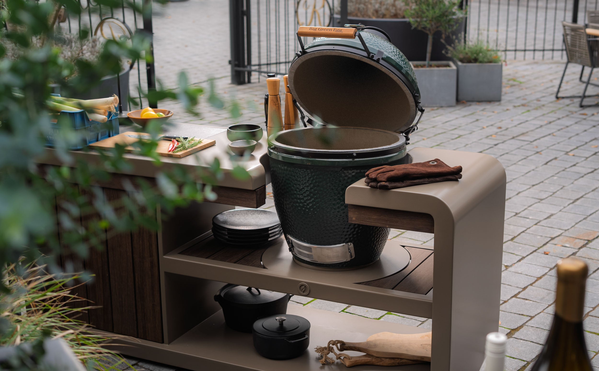 Outdoor setting with a large green barbecue grill on a wooden table.