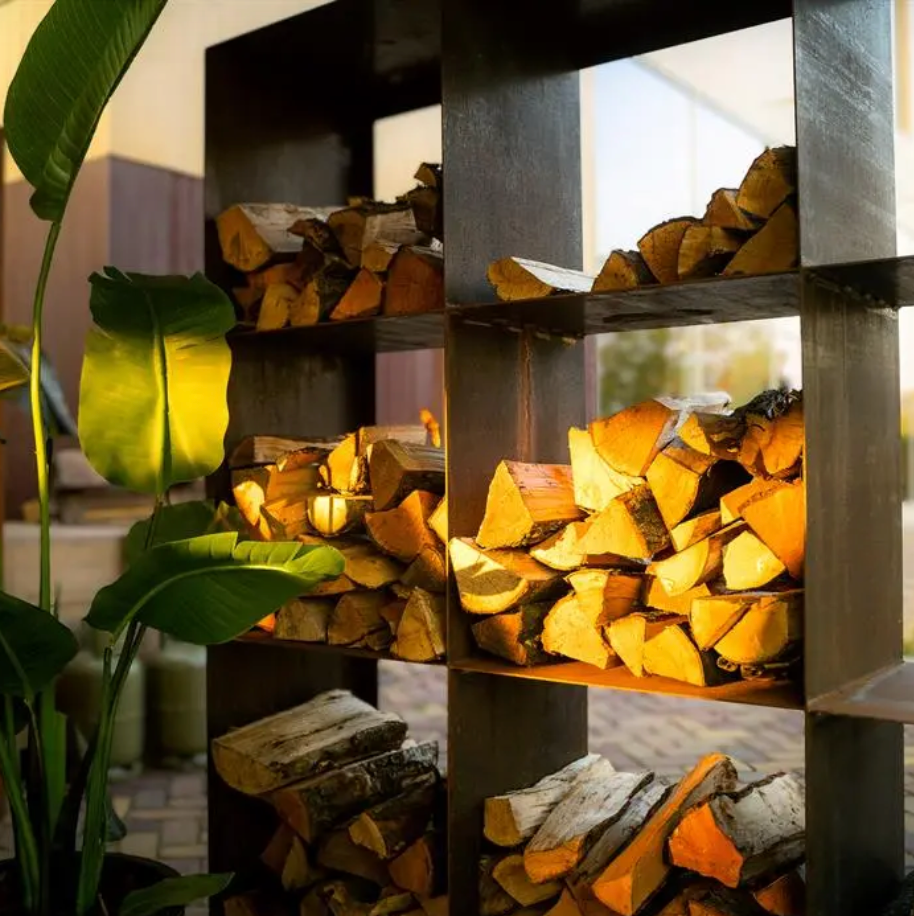Stack of chopped wood in a metal fire pit with plants in the foreground