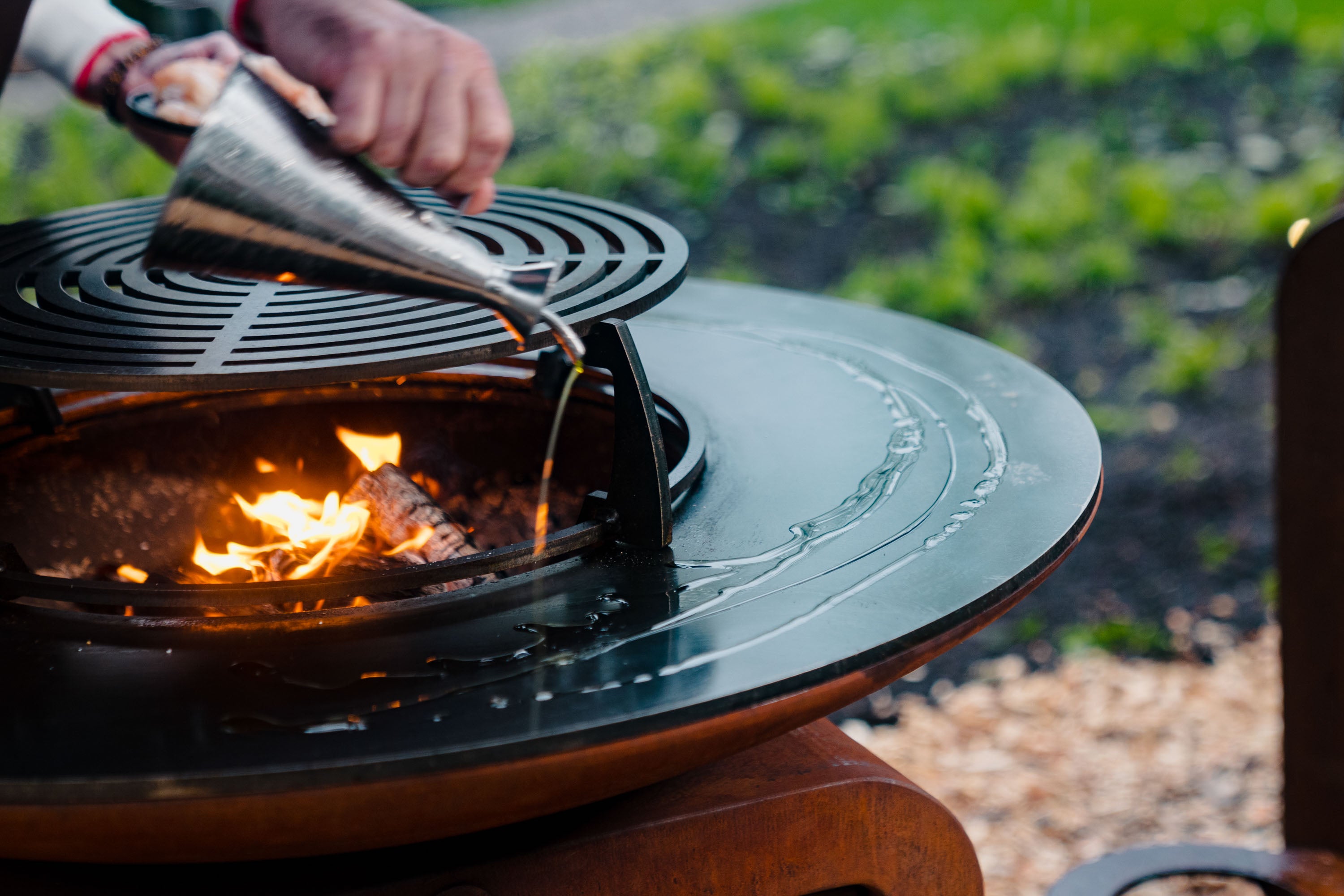 Person using a funnel to add oil to grill