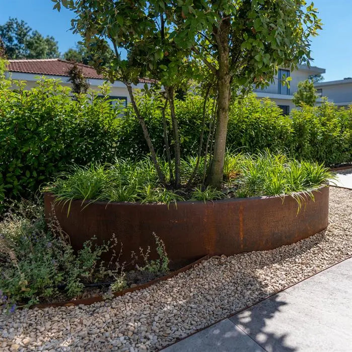 oval rusted planter with tree on gravle