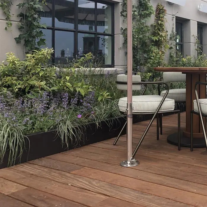 black retaining wal with established plants on decked patio