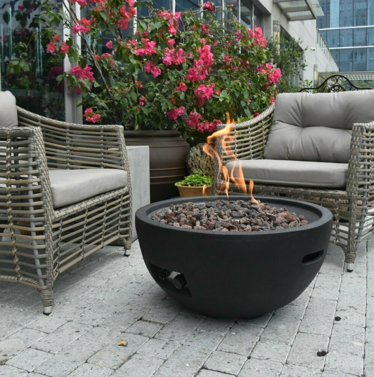 round black gas fire bowl alight surrounded by garden furniture