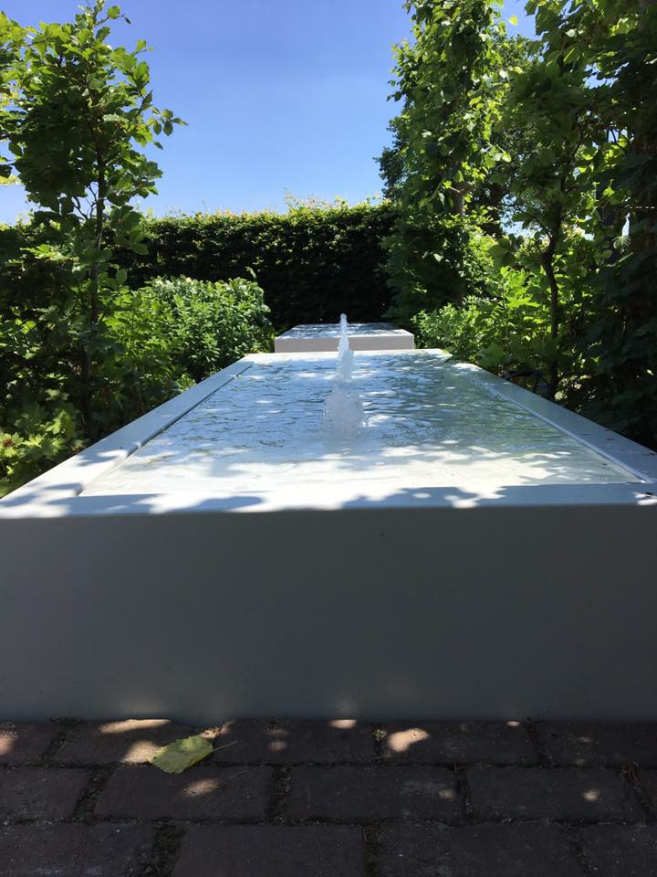 long rectangular white water table filled with water with fountains