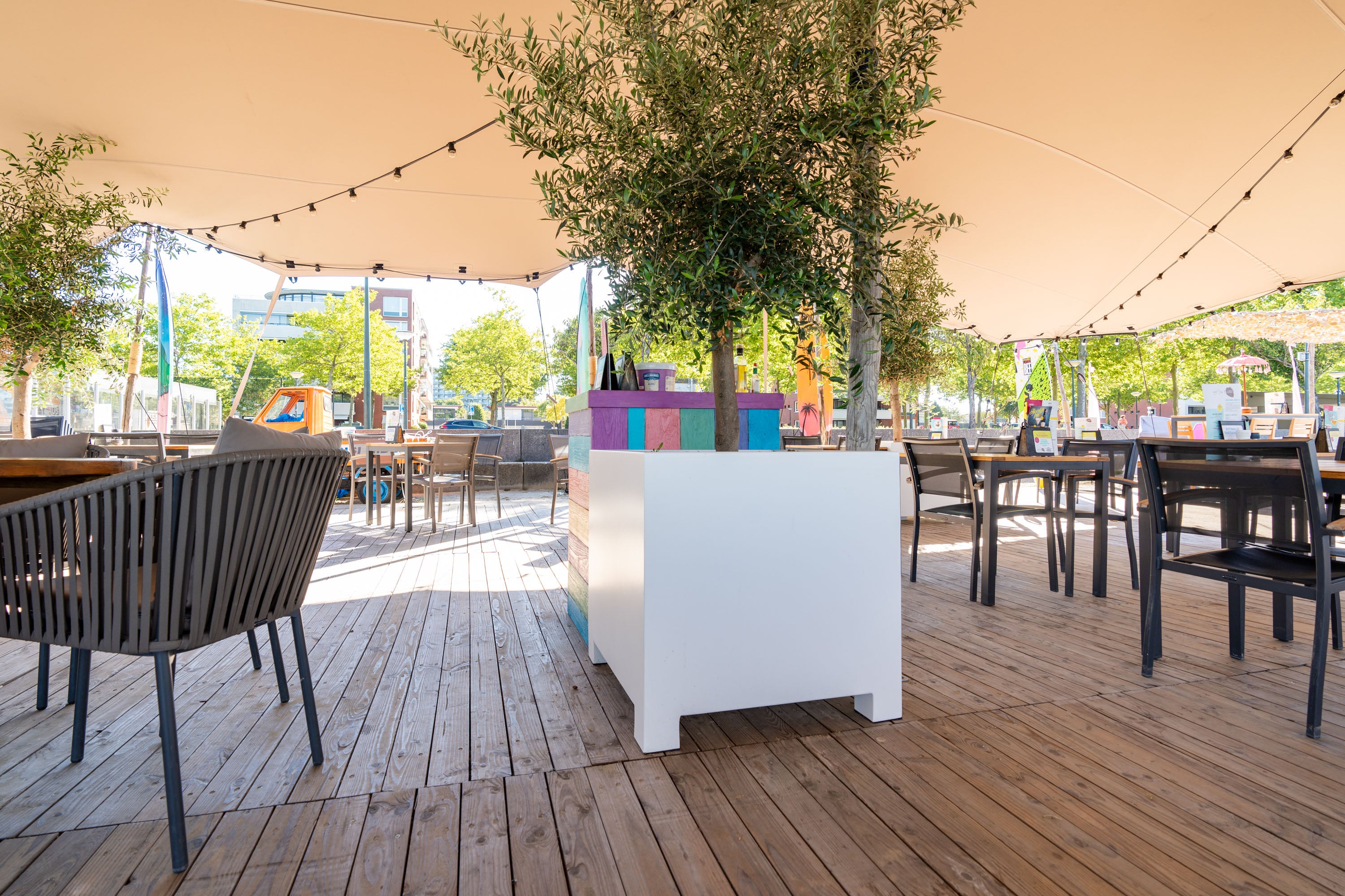 Outdoor seating area with tables, chairs, and a white partition on a wooden deck.