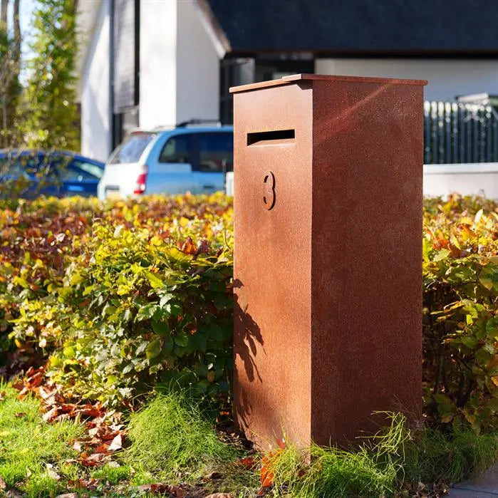 freestanding cprten postbox next to hedge on street