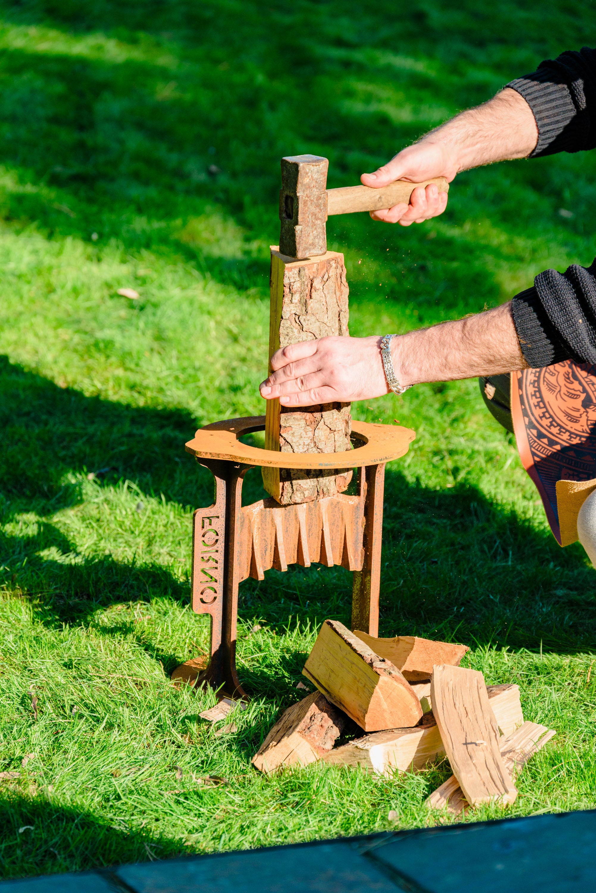 Person using a corten log splitter on a grassy area