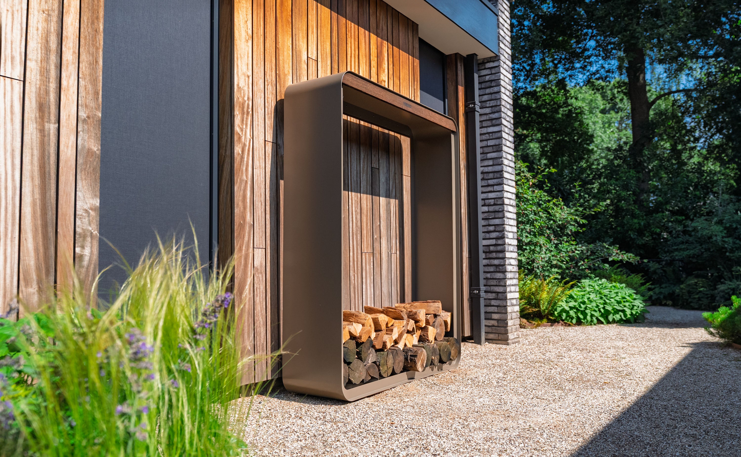 Wooden firewood storage unit against a modern building with greenery around