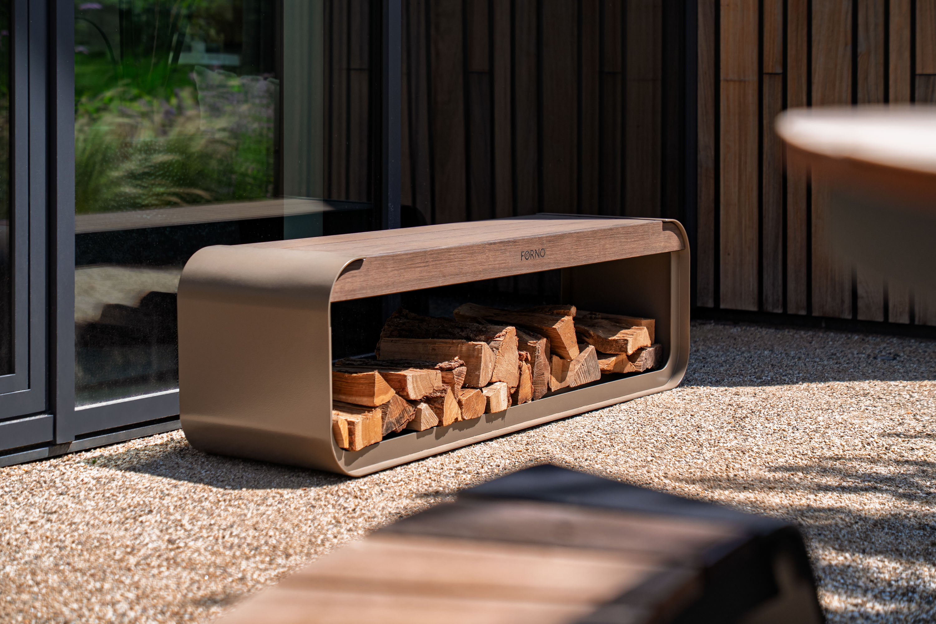 Wooden firewood storage bench with firewood inside, placed on a concrete surface.