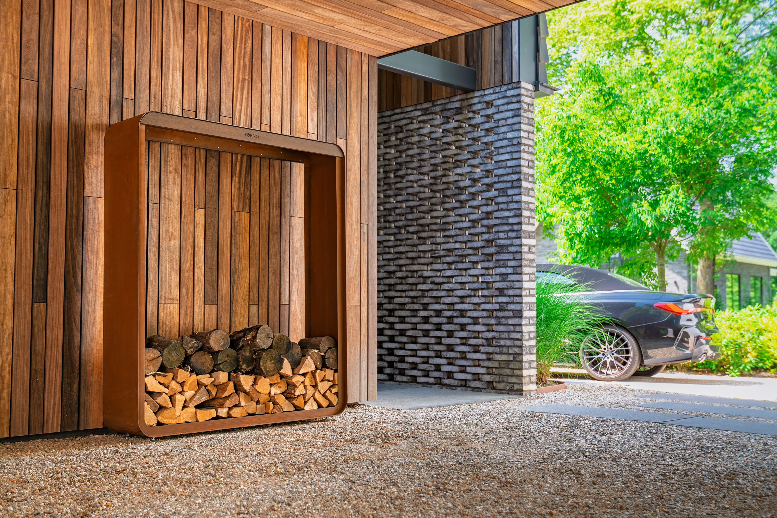 Wooden firewood storage unit against a modern building with a car parked outside.