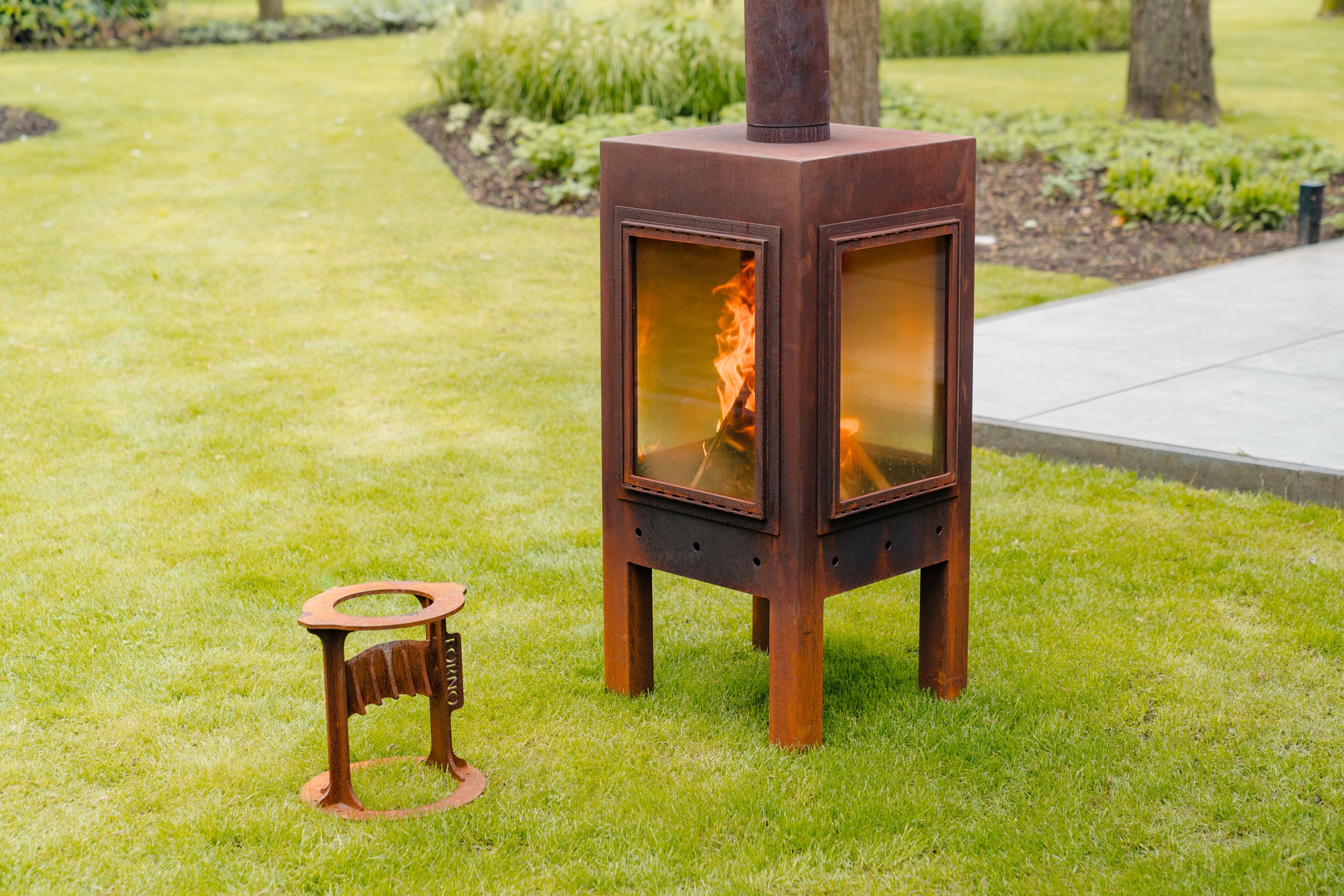 Wood-burning stove with fire inside on a grassy lawn