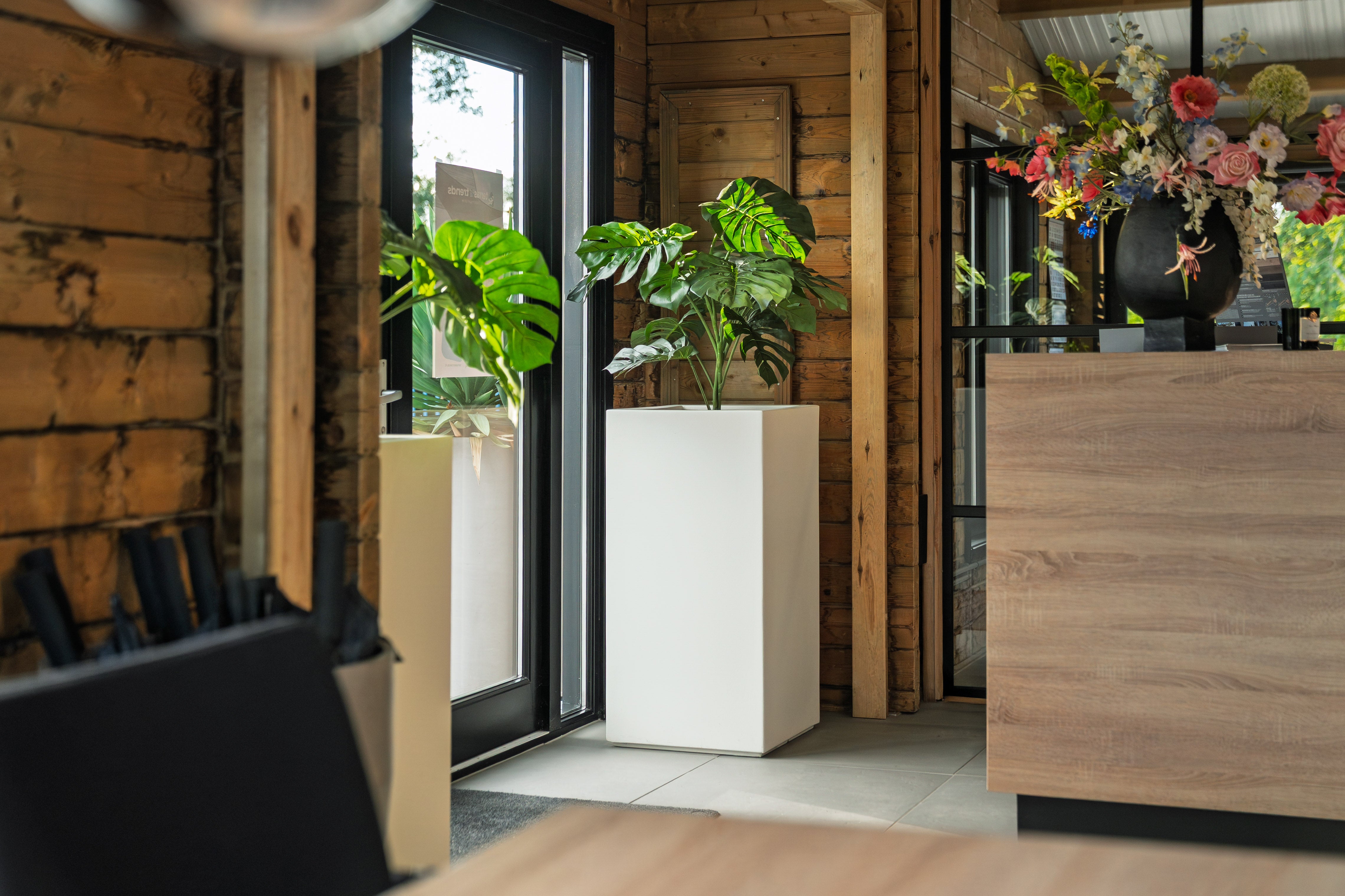 Modern interior with wooden furniture, plants, and a glass door.