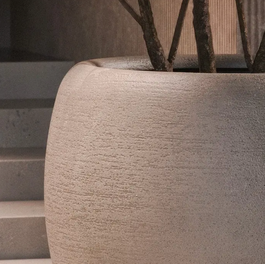 Textured stone planter with branches on a neutral background