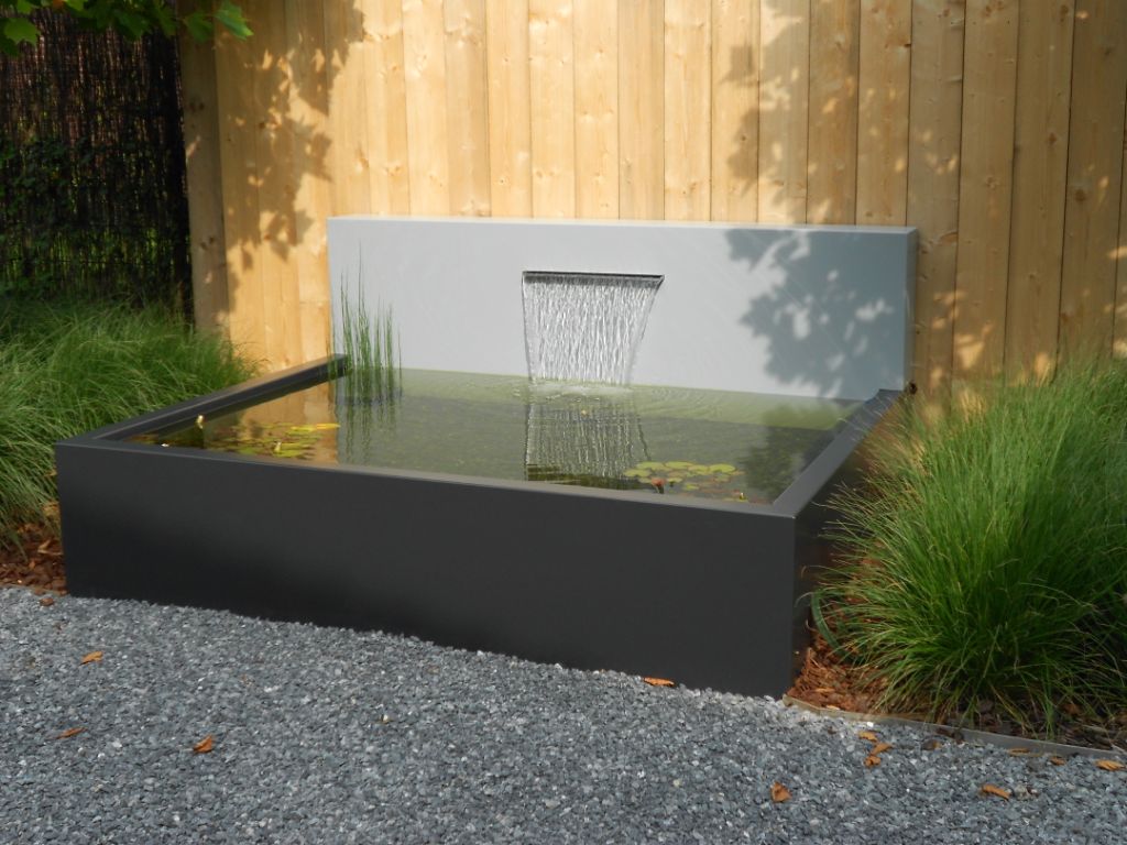Modern water feature with a glass panel in a garden setting