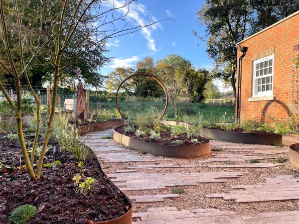 Garden with circular metal planters and wooden pathway