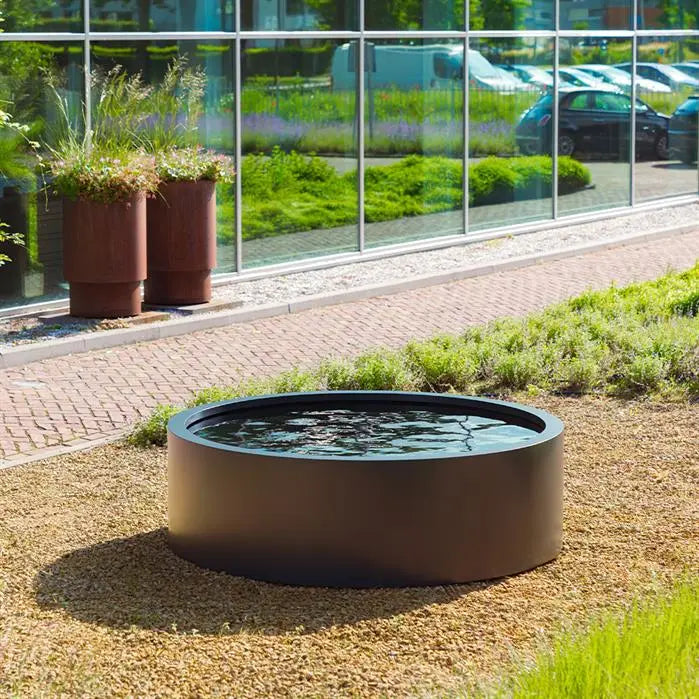 black round aluminium pond filled with water set on gravel