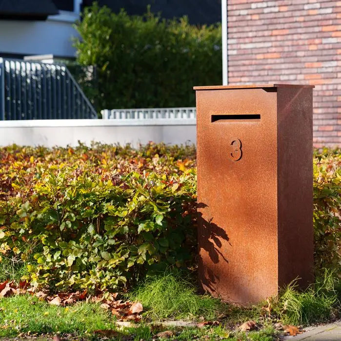 corten letterbox next to hedge outside house