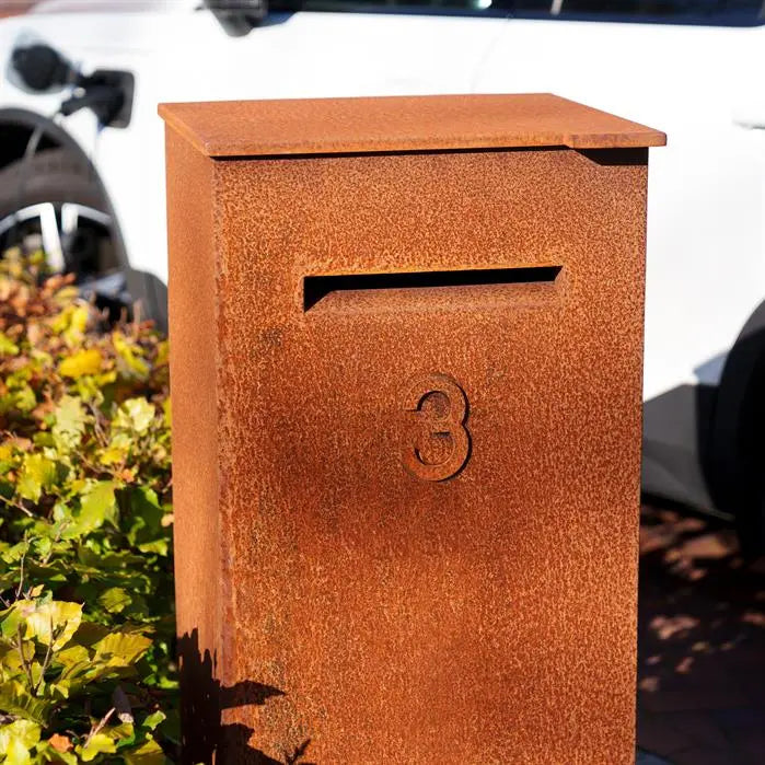 close up of corten leterbox with house number on it