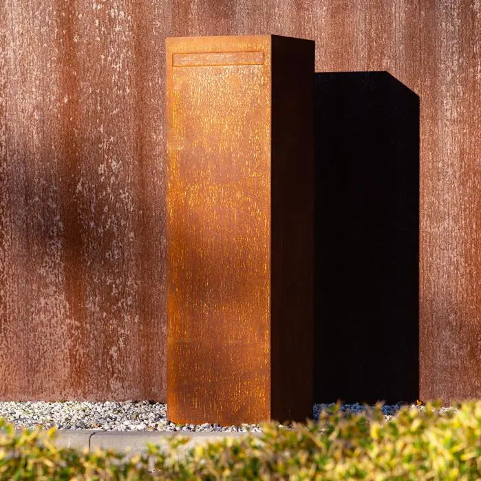 letterbox in corten set against a brown wall on gravel