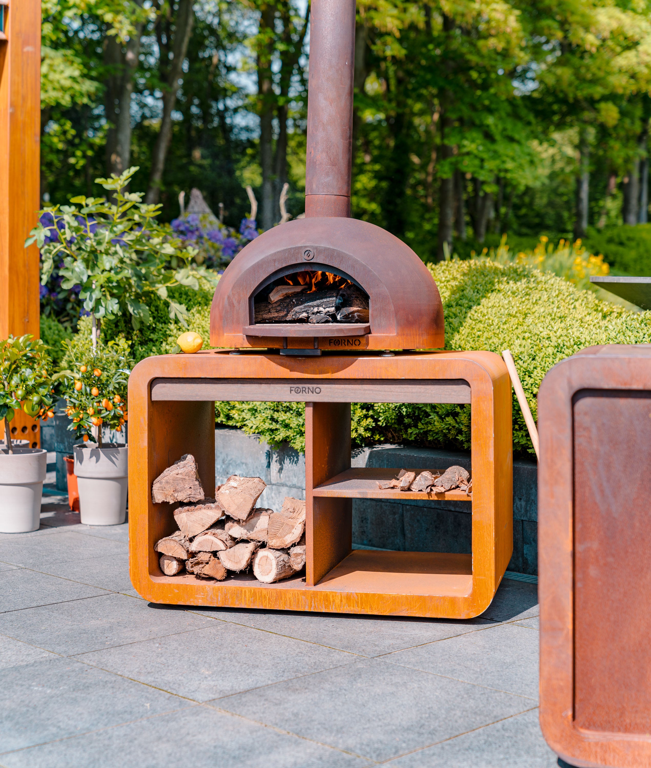 Outdoor pizza oven with firewood storage on a patio