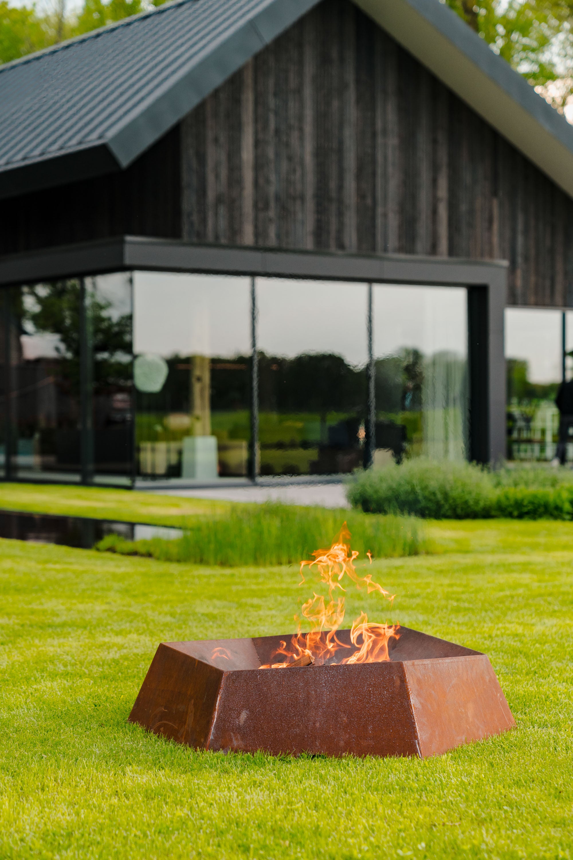 angular fire bowl alight on lawn in front of a house