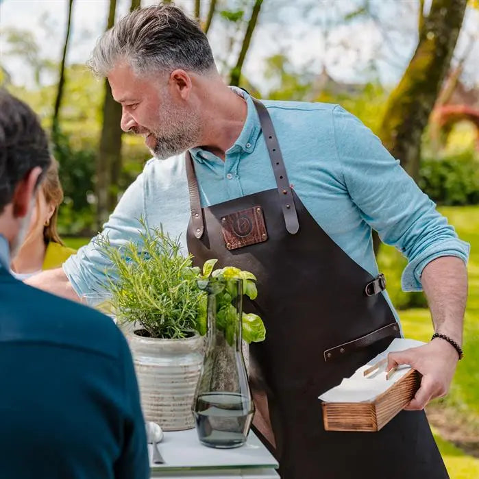 man wearing a leather apron next to a table