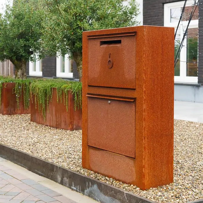 corten letterbox with number on it also in corten set on raised gravel bed next to the pavement