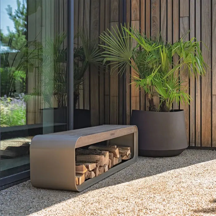 Modern outdoor bench with firewood storage next to a potted plant in a garden setting.