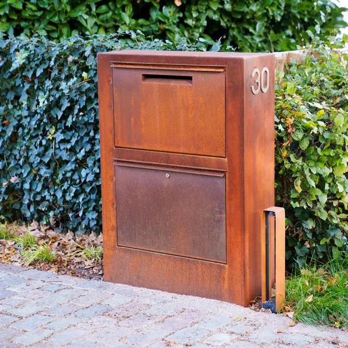 corten letterbox with a posting slot and locked box underneath set next to the driveway