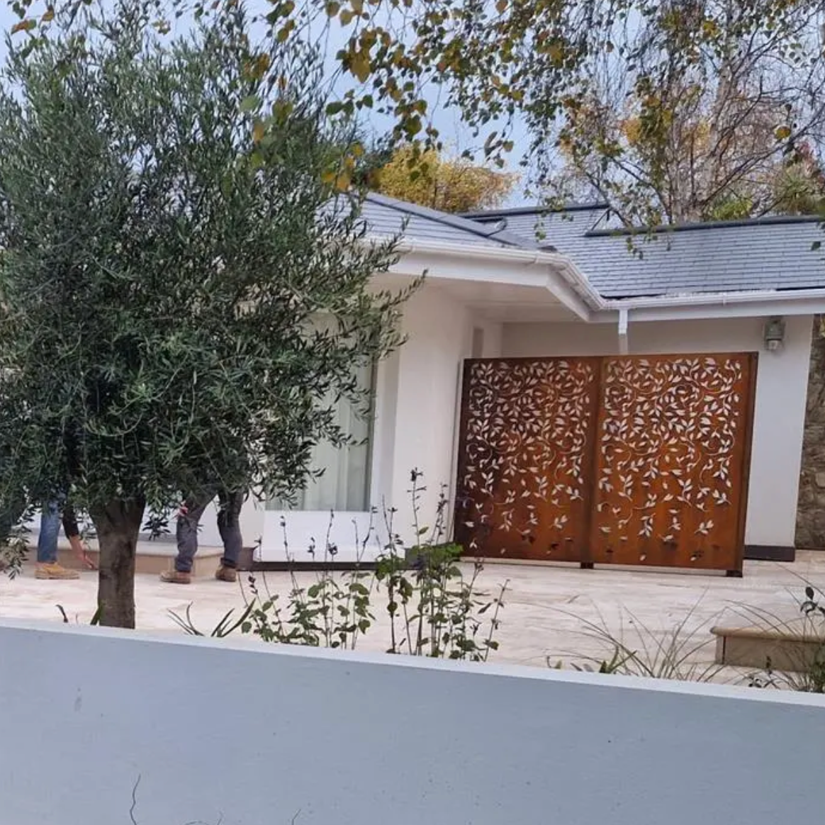 Modern house with decorative metal screen in front of a tree