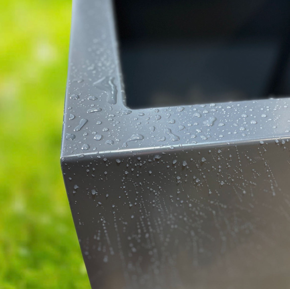 Close-up of a gray rectangular object with water droplets on a blurred green background