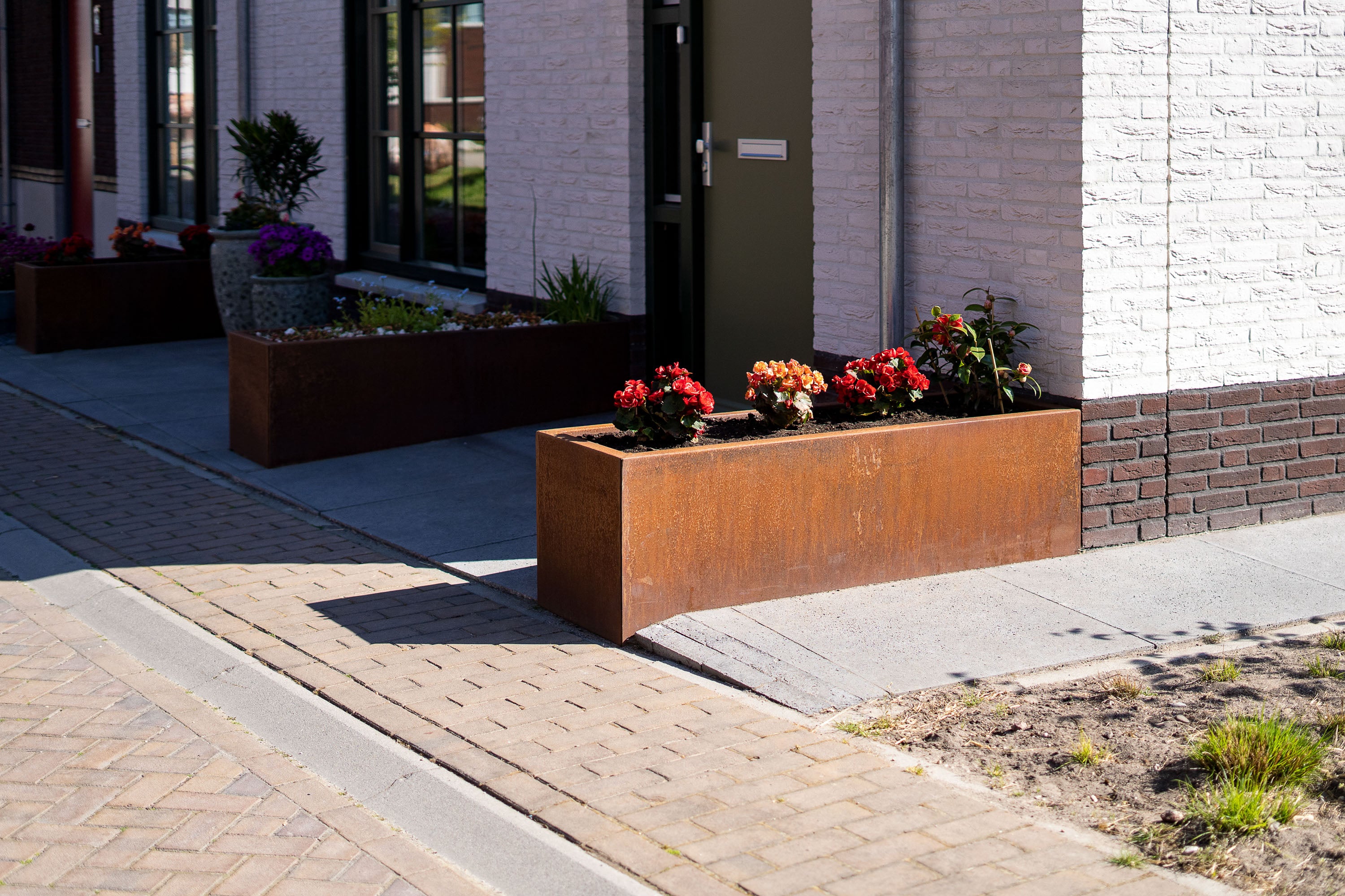 two rusted garden trough planters wither side of a door with plants