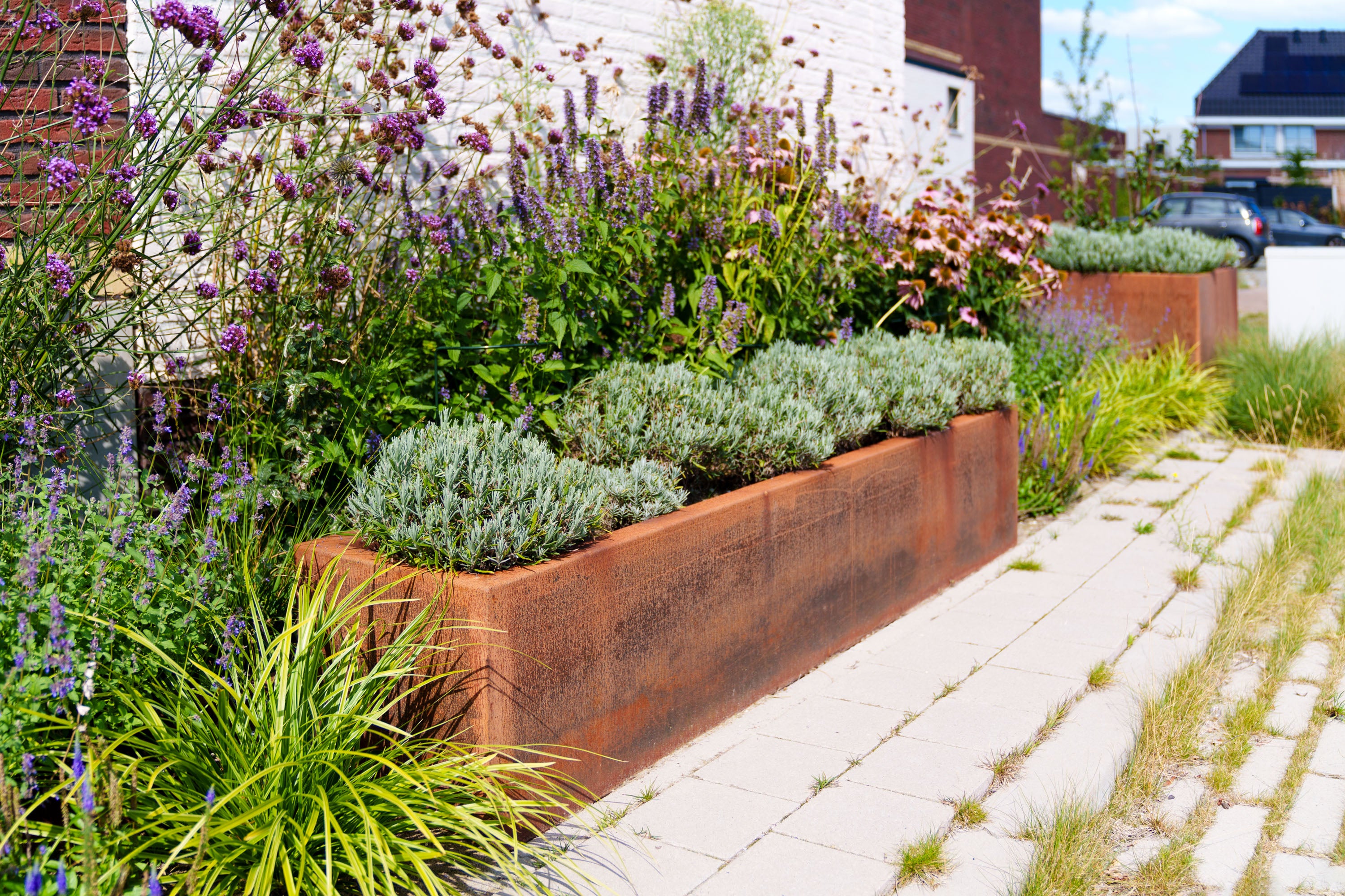Decorative garden with metal planters filled with flowers and plants on a sidewalk.