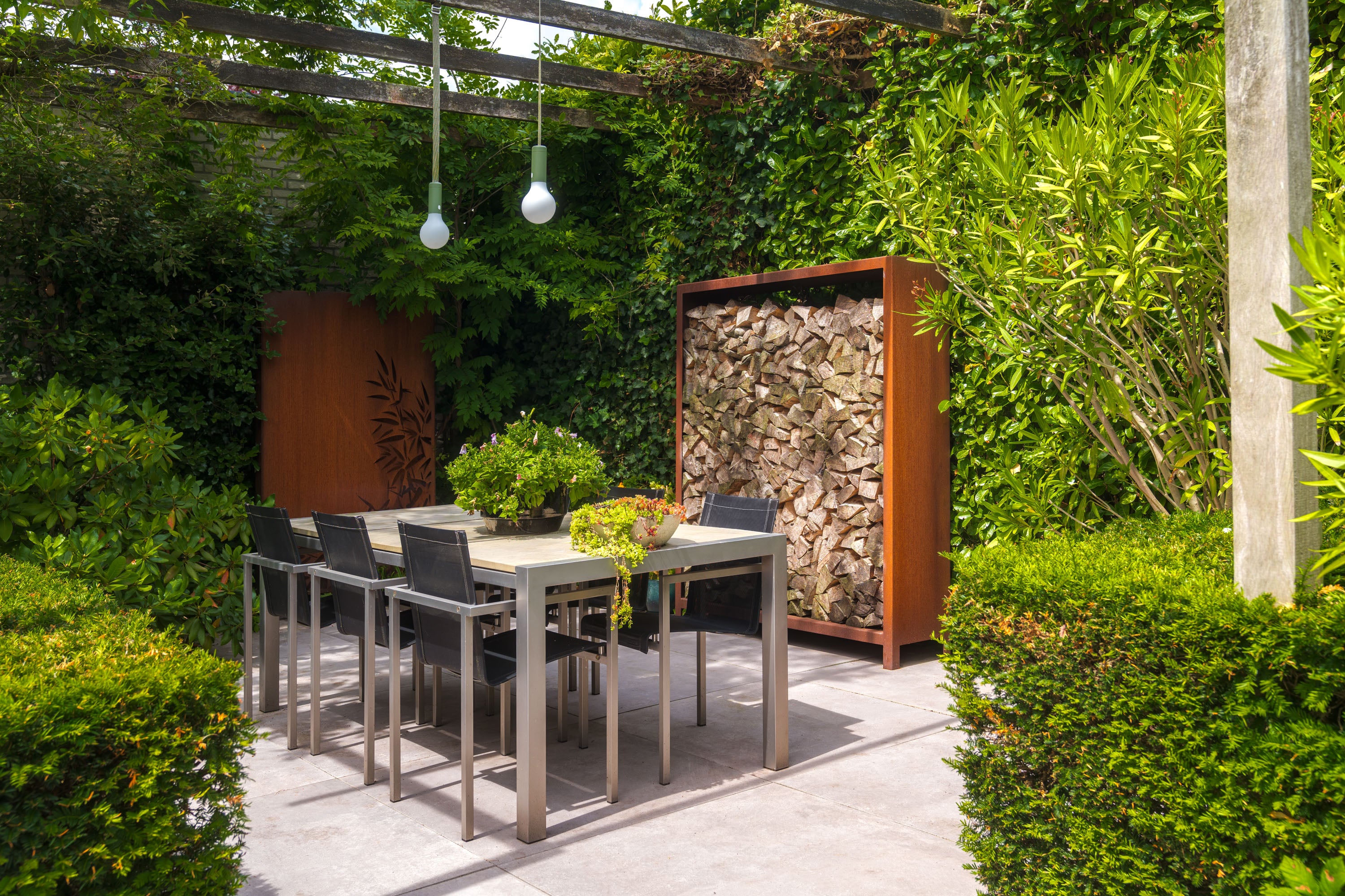 Outdoor patio setting with a dining table and chairs surrounded by greenery.