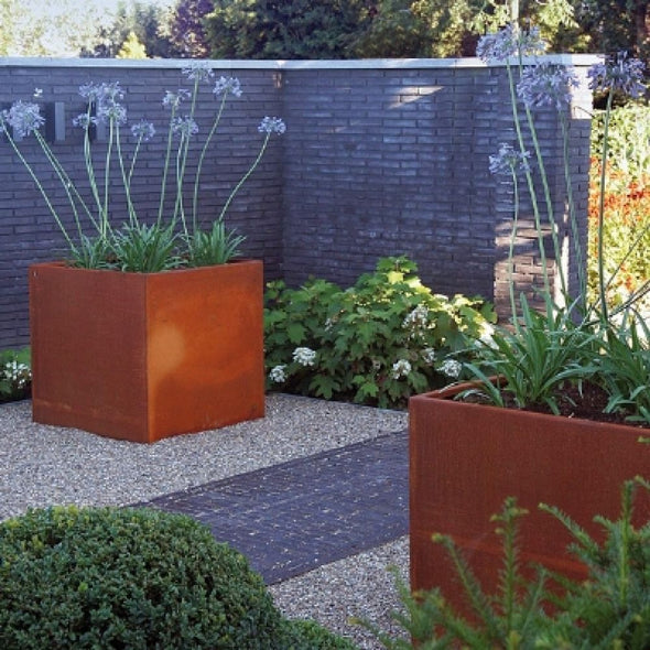 two corten steel garden planters in landscaped garden 