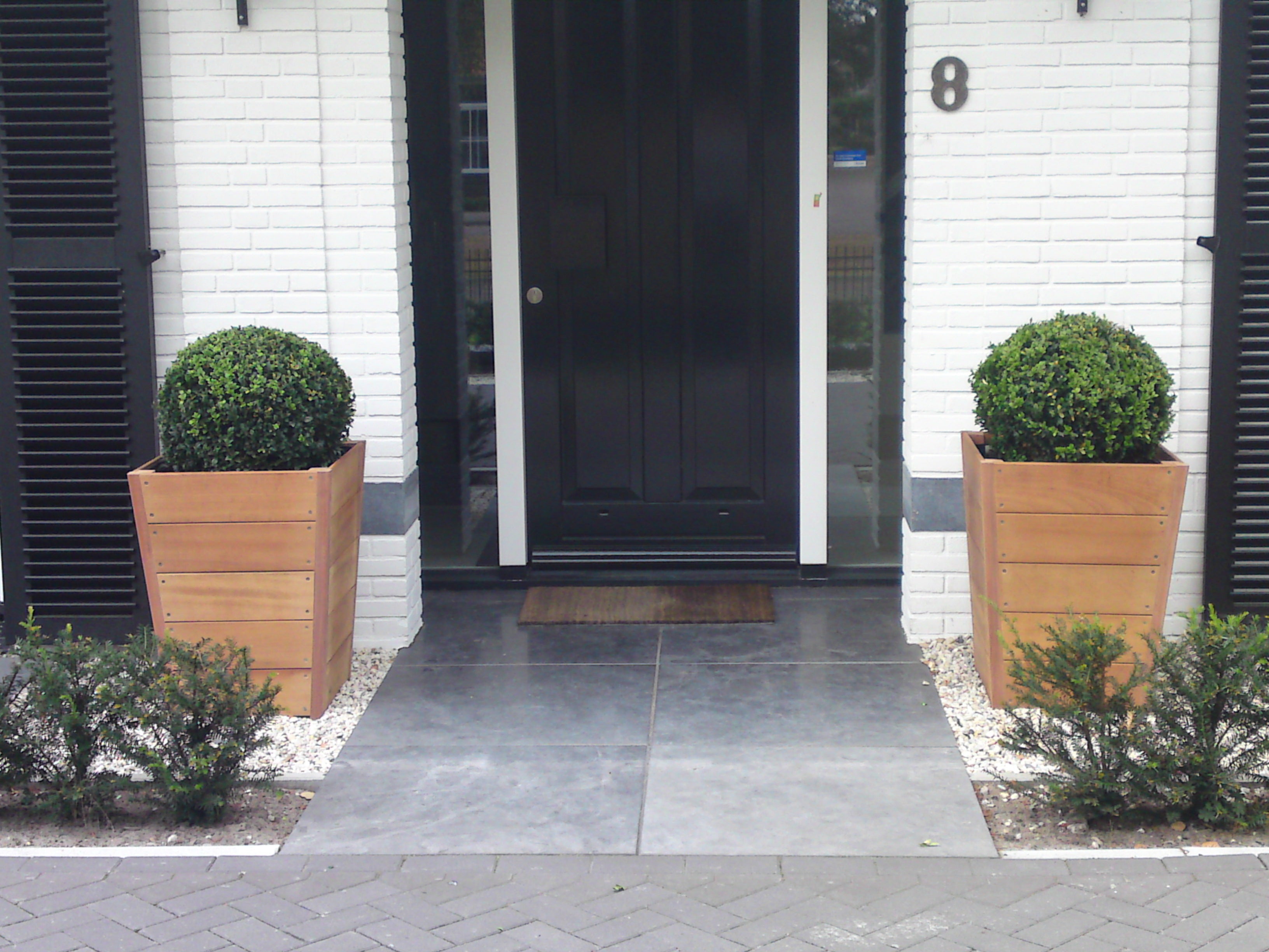 two tapered hardwood garden planters either side of a door way 