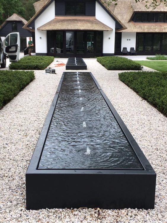 long black aluminium water table filled with water and fountains along the middle