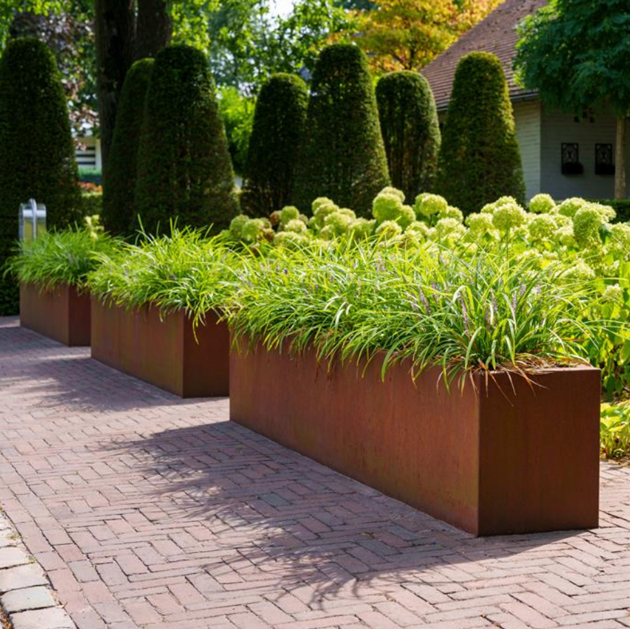 three corten steel trough garden planters, planted with grasses