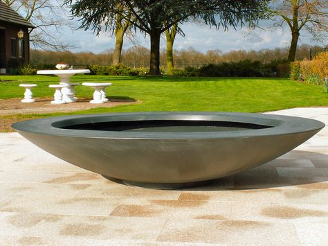 black dish fiberglass garden planter situated in garden