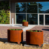 two round corten steel garden planters with feet