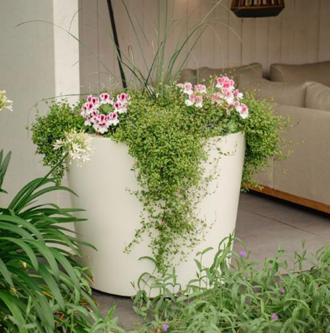 white conic fiberglass planter filled with plants