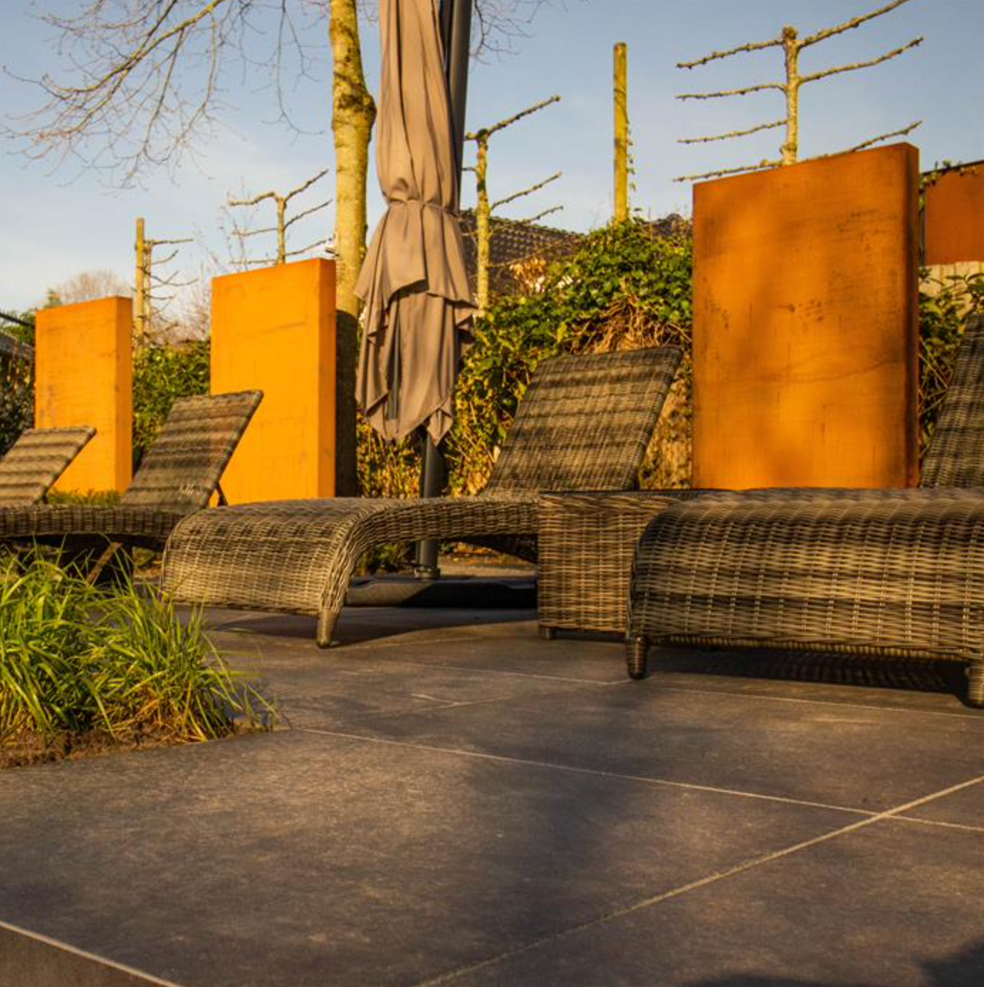three corten steel feature walls in garden behind sun loungers