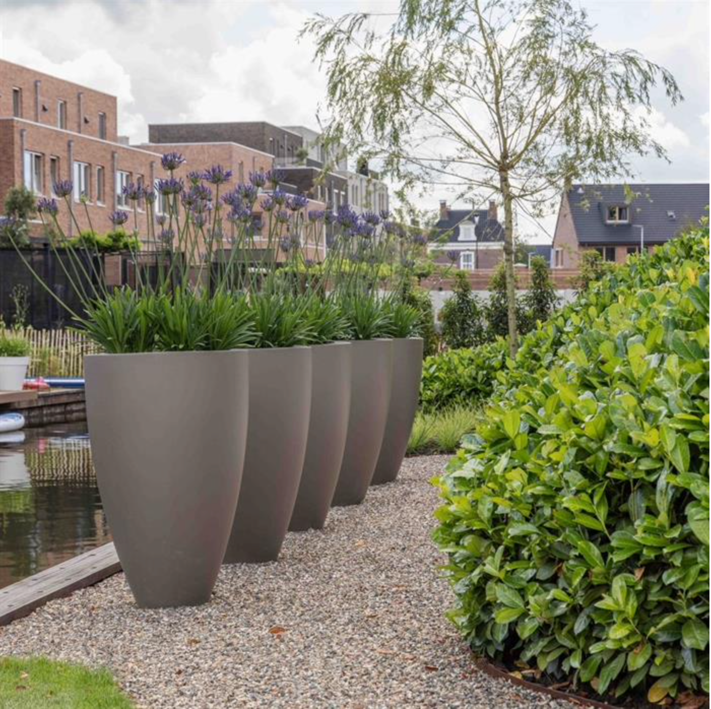 row of five tall grey fiberglass planters